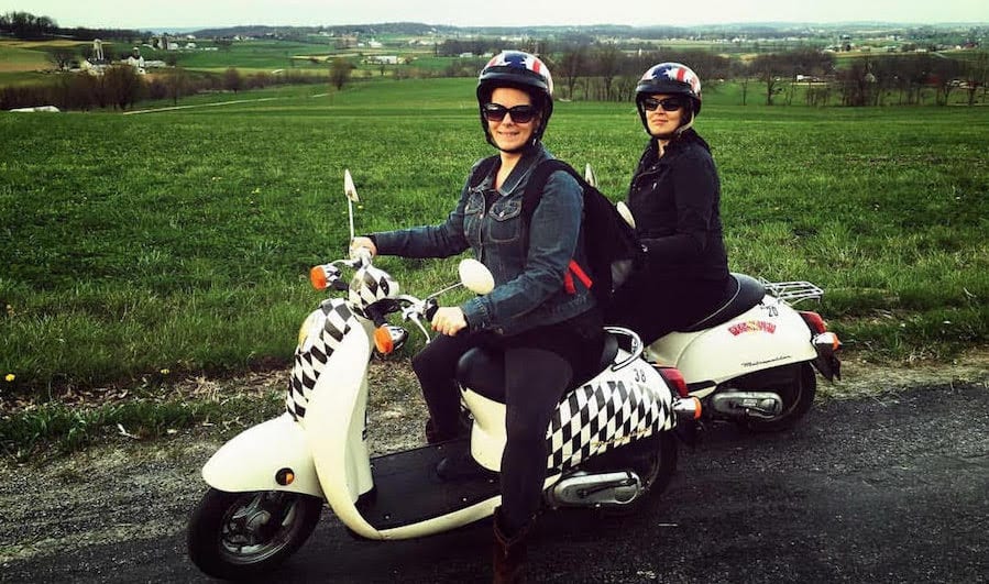 Two riders astride scooters